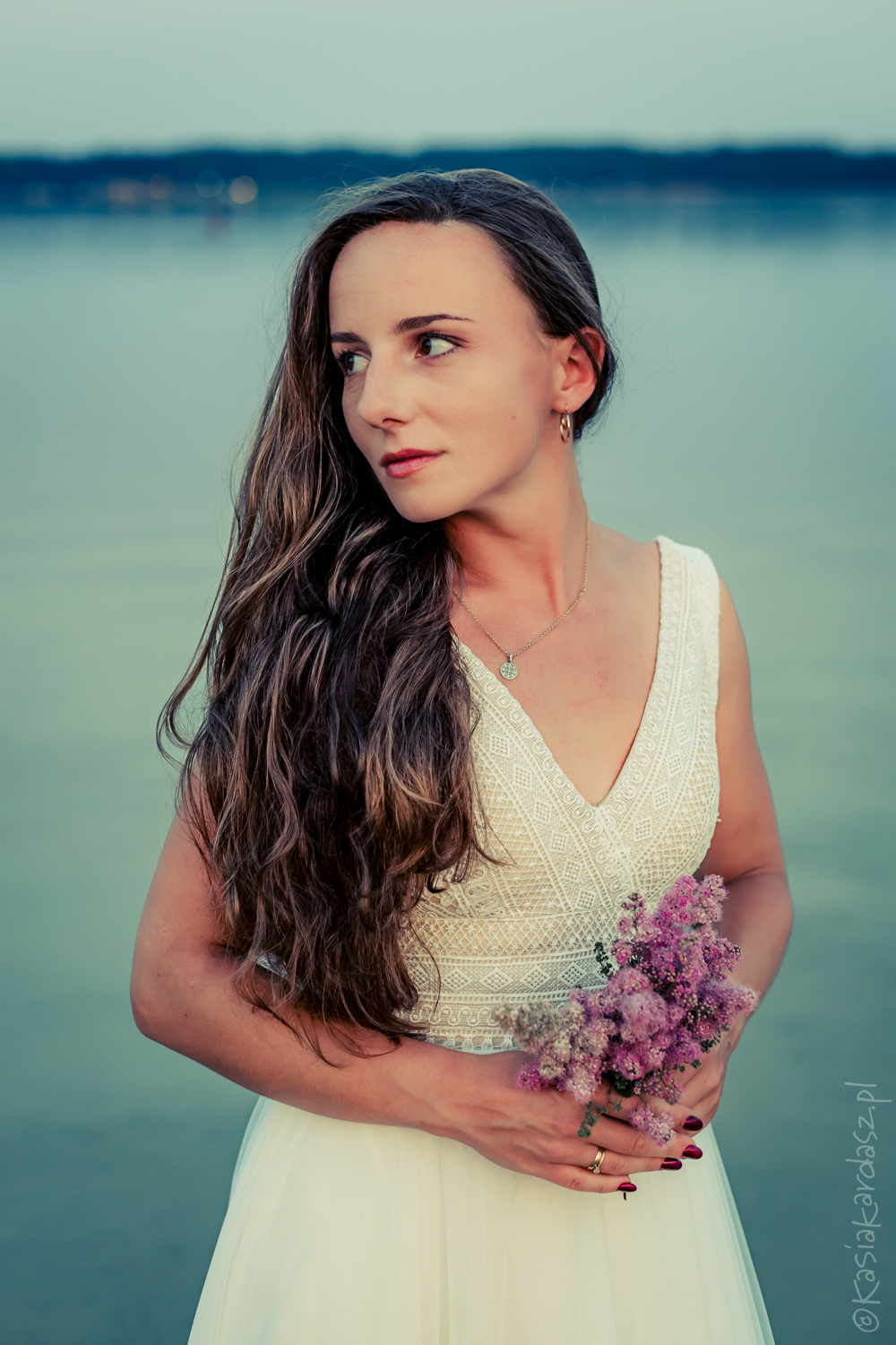 Portret panny młodej podczas sesji ślubnej w jeziorze o zachodzie słońca; romantyczna fotografia ślubna w plenerze.