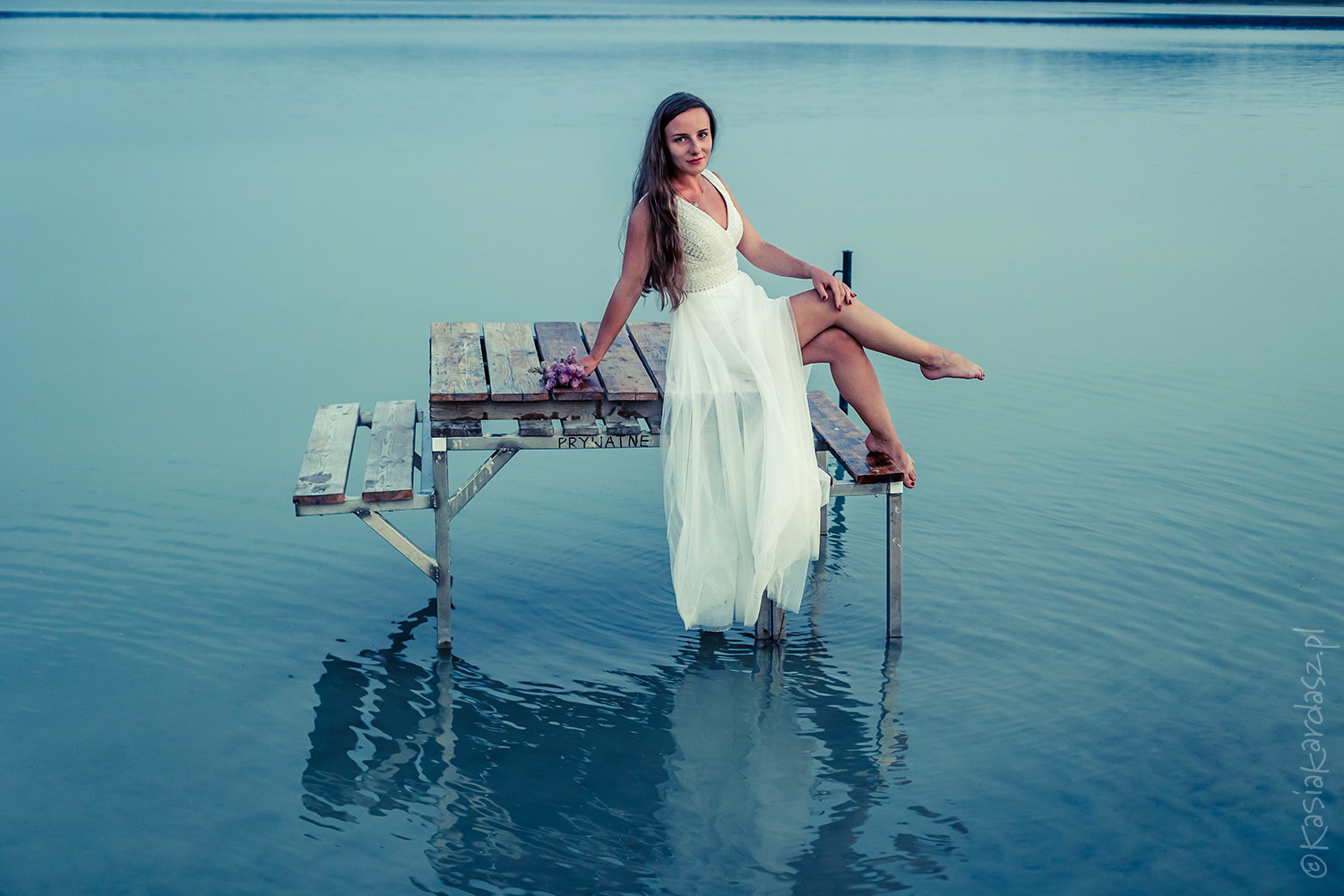 Panna młoda zanurzona w jeziorze, otulona ciepłem zachodzącego słońca; chwila ciszy, wzruszenia i piękna.