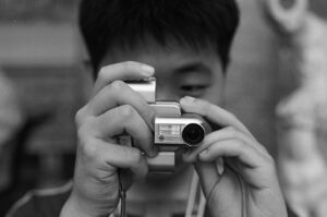 Mężczyzna z aparatem analogowym w bazylice św. Piotra w Watykanie. Fotografia czarno-biała. Negatyw