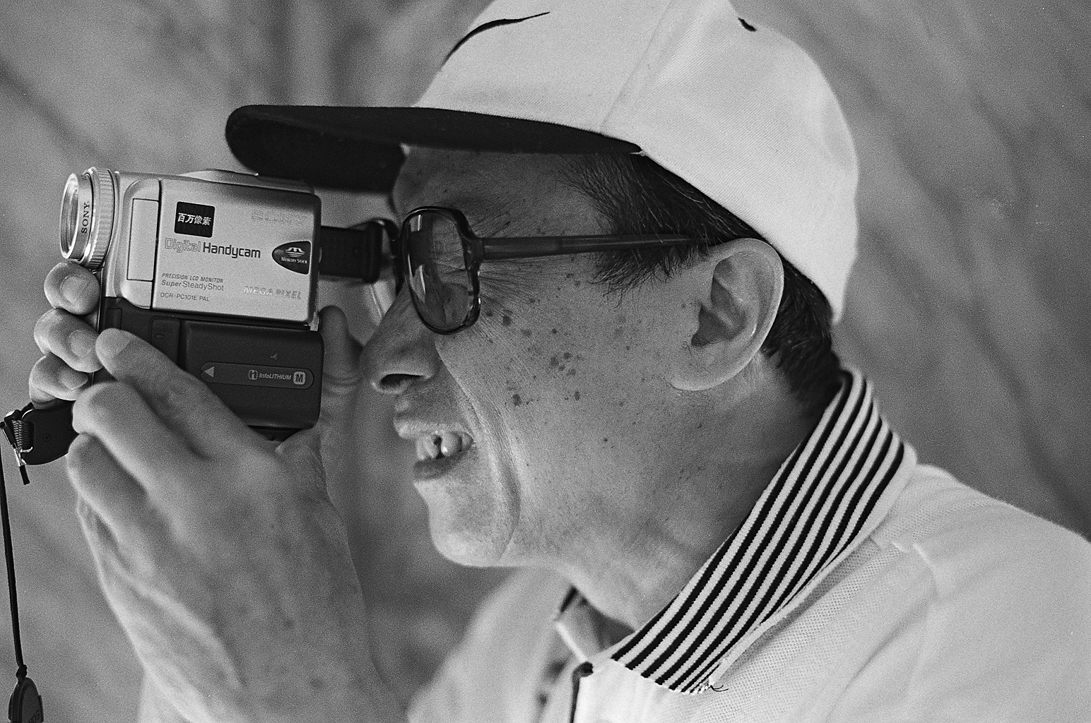 Mężczyzna typu azjatyckiego z kamerą analogową w bazylice św. Piotra w Watykanie. Fotografia czarno-biała. Negatyw