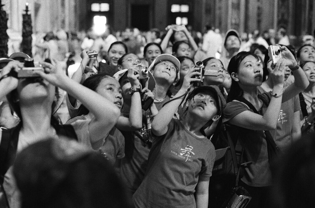 Tłum fotografujących azjatów w bazylice św. Piotra w Watykanie. Fotografia czarno-biała. Negatyw