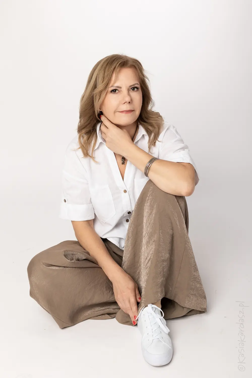 kobieta siedząca na podłodze w bieli i brązie