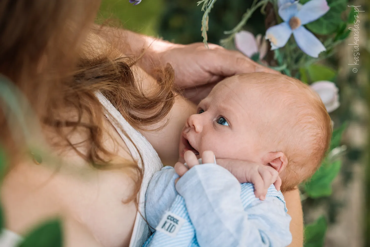 Noworodek w niebieskim ubranku uśmiecha się do mamy
